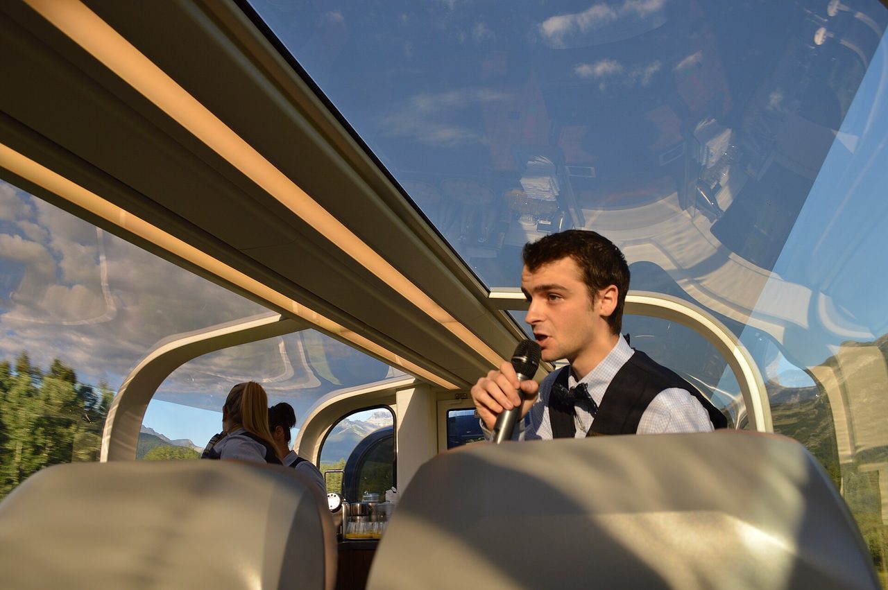 An onboard host narrating beneath the full glass dome of a GoldLeaf coach